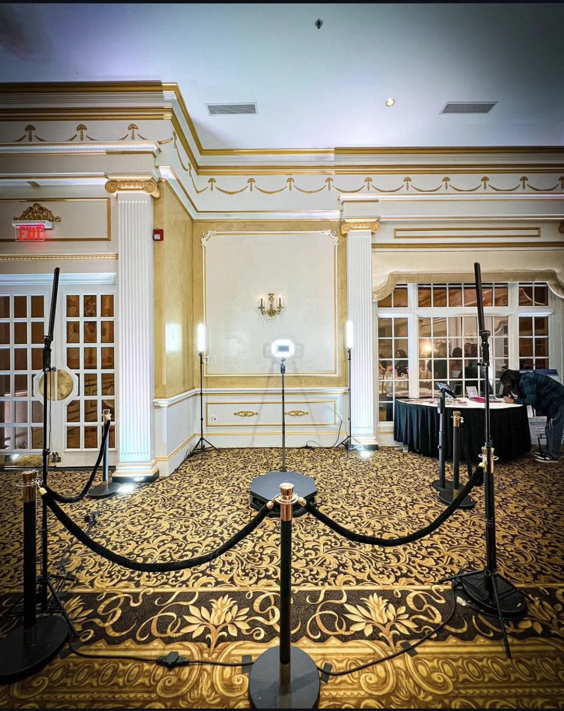 A 360 video booth platform with lighting and velvet stanchions in an ornate ballroom